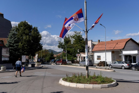 Una mujer serbia pasa junto a banderas nacionales serbias en una rotonda en la ciudad de Zvecan, cerca de Mitrovica, en Kosovo, el 19 de septiembre de 2022.