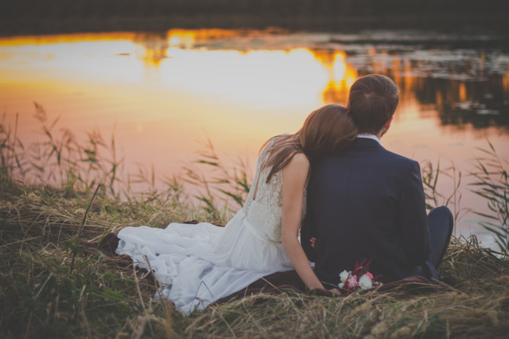 La novia y el novio se sientan junto al estanque