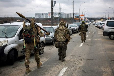 Los militares ucranianos llevan granadas propulsadas por cohetes y rifles de francotirador mientras caminan hacia la ciudad de Irpin, al noroeste de Kyiv, el 13 de marzo de 2022.