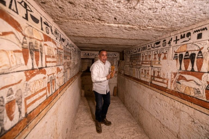 Mostafa Waziri, jefe del Consejo Supremo de Antigüedades de Egipto, sostiene una pequeña estatuilla el 19 de marzo de 2022, dentro de una de las cinco antiguas tumbas faraónicas descubiertas recientemente en el sitio arqueológico de Saqqara, al sur de la 