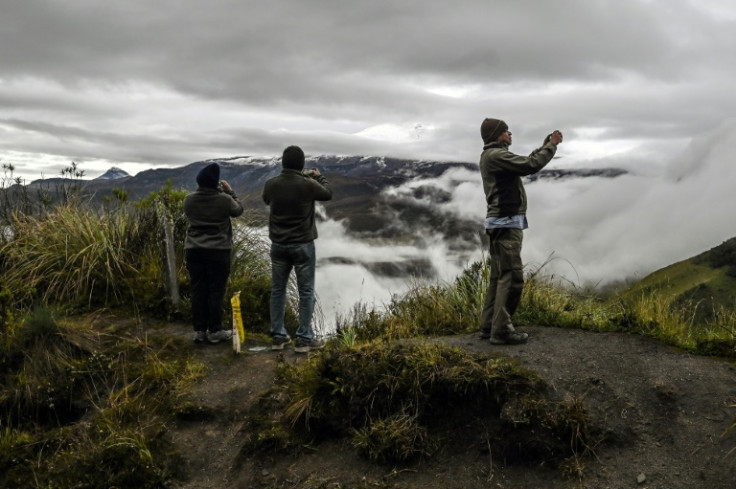 Turistas toman fotos del volcán Nevado del Ruiz mientras emite columnas de humo