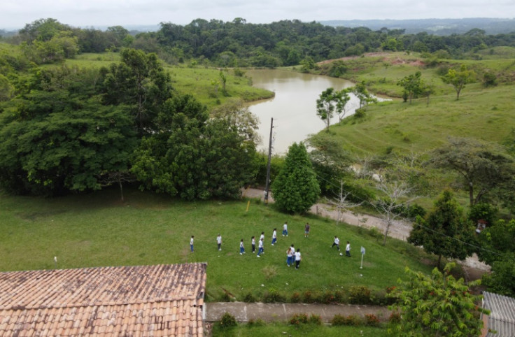 Vista aérea que muestra a alumnos en Colombia jugando en una escuela junto a un lago donde los hipopótamos permanecen en estado salvaje