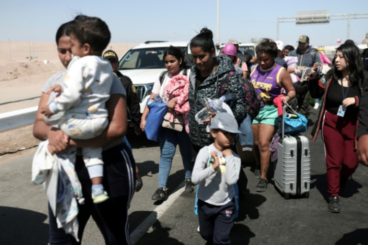 Migrantes de diferentes nacionalidades son escoltados por policías peruanos a una oficina de migración en Tacna, en la frontera entre Perú y Chile en abril de 2023