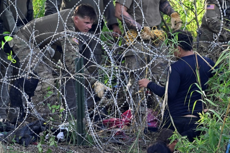Un migrante que cruzó el Río Grande es detenido por miembros de la Guardia Nacional de EE. UU. que refuerzan una cerca de alambre de púas a lo largo del río en la frontera entre EE. UU. y México, visto desde Matamoros, estado de Tamaulipas, México, el 10 