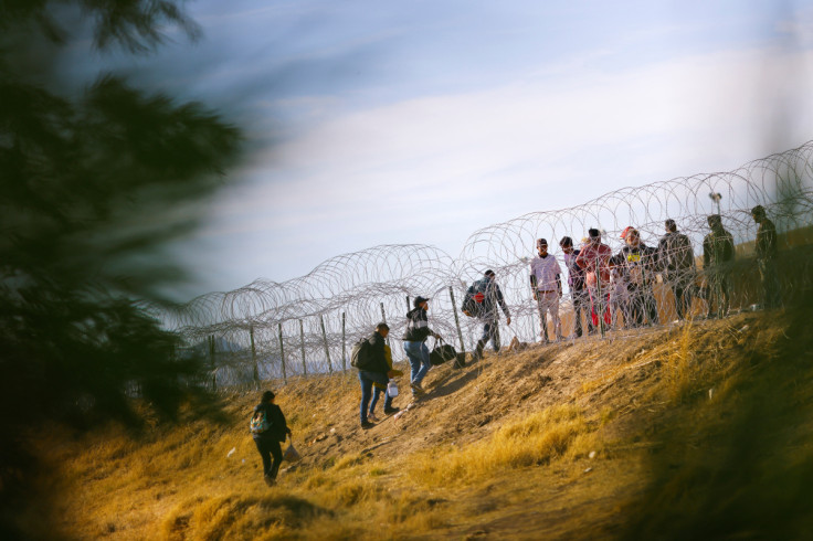 Migrantes se paran cerca del muro fronterizo, visto desde Ciudad Juárez