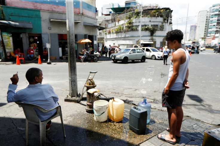 La gente saca agua de una boca de incendios, en Caracas