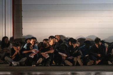 Migrantes esperan un autobús que los lleve a un centro de procesamiento después de que se entregaron a los agentes de la Patrulla Fronteriza de EE. UU. después de cruzar desde México en Frontón, Texas.