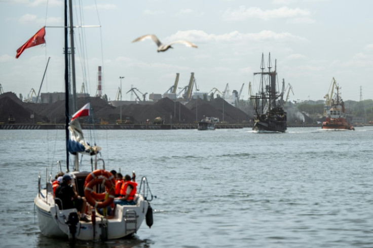 Los barcos turísticos pasan por el puerto de Gdansk, Polonia, con sus enormes pilas de carbón