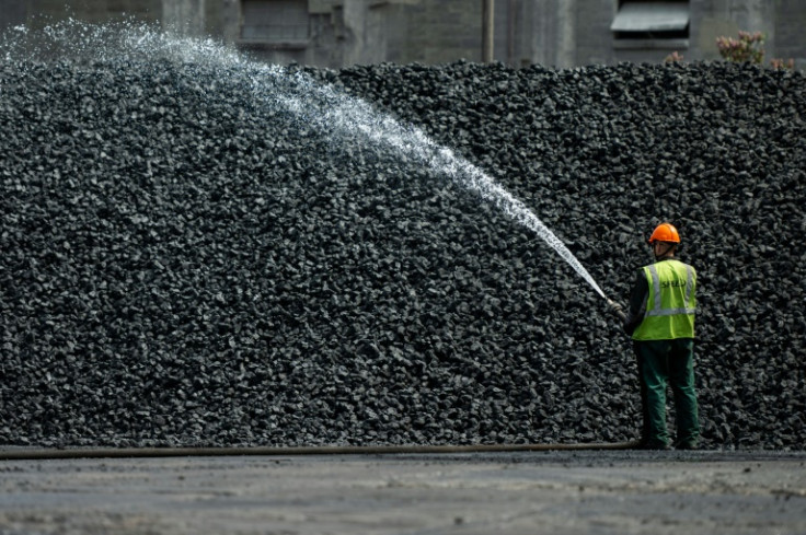 Un trabajador rocía un montón de carbón con agua en Gdansk, Polonia, para amortiguar el polvo.