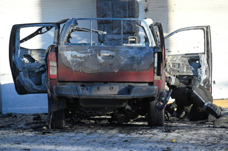 Policía inspecciona los restos de un auto quemado frente a la sede del SNAI en Quito